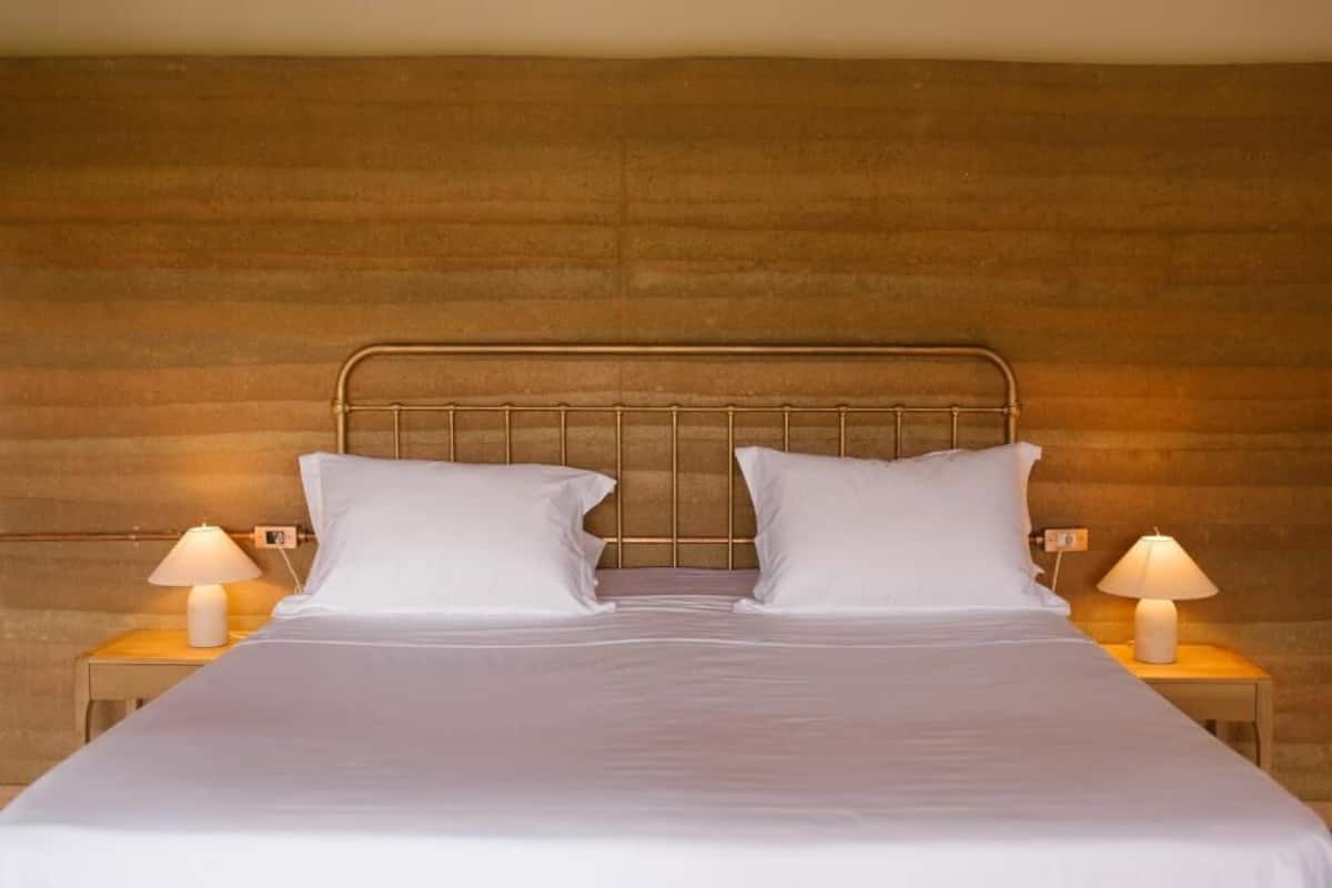 A bed with a metal headboard, two white pillows, and two bedside lamps on wooden nightstands.