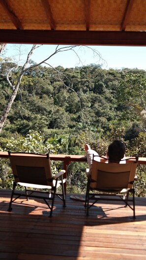 Two wooden chairs facing a lush green forest from a wooden deck. - Canto dos Pireneus Hospedaria (Pirenopolis)