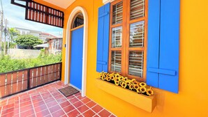 Ein gelbes Gebäude mit blauen Fensterläden und einem Fenster mit Sonnenblumen.