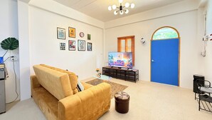 Ein Wohnzimmer mit einer Couch, einem Fernseher und Kunstwerken an der Wand.