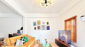 Ein Wohnzimmer mit Sofa, Fernseher und Wandbildern.