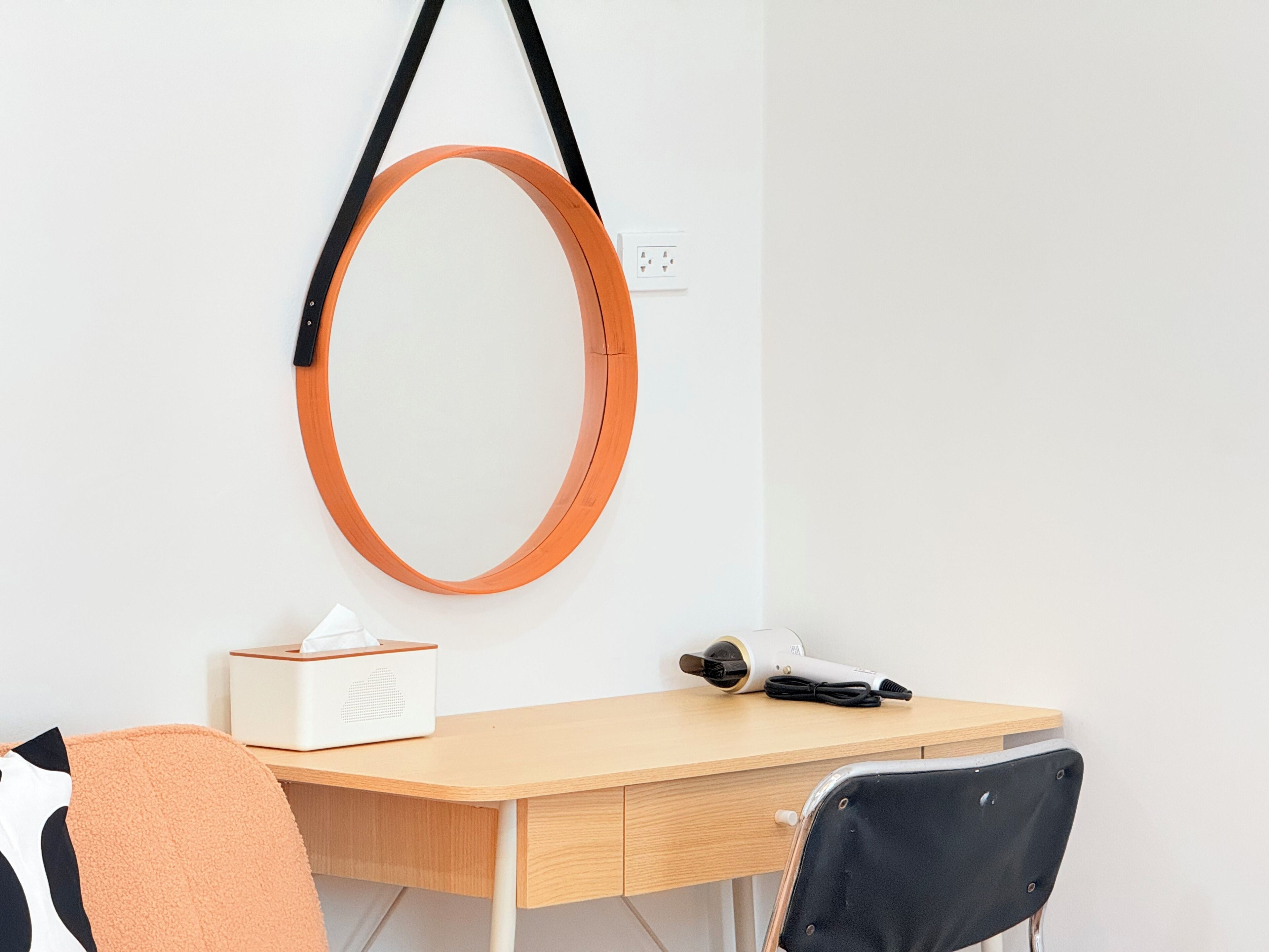 A room with a desk, chair, and a wall-mounted mirror.