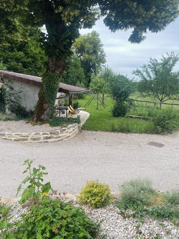 A garden with a stone wall, a tree, and a wooden structure. - Comfortable gîte in a peaceful mountain setting (Graye-et-Charnay)
