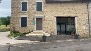 Un edificio de piedra con puerta de madera, un pequeño porche y un letrero que indica una ubicación urbana.