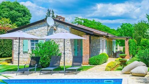 Una casa de piedra con piscina, mobiliario de exterior y jardín.