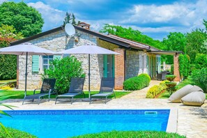 Ein Steinhäuschen mit Pool, Außenbereich und Garten.