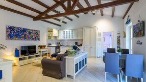 Una sala de estar moderna con televisor, sofá y comedor.