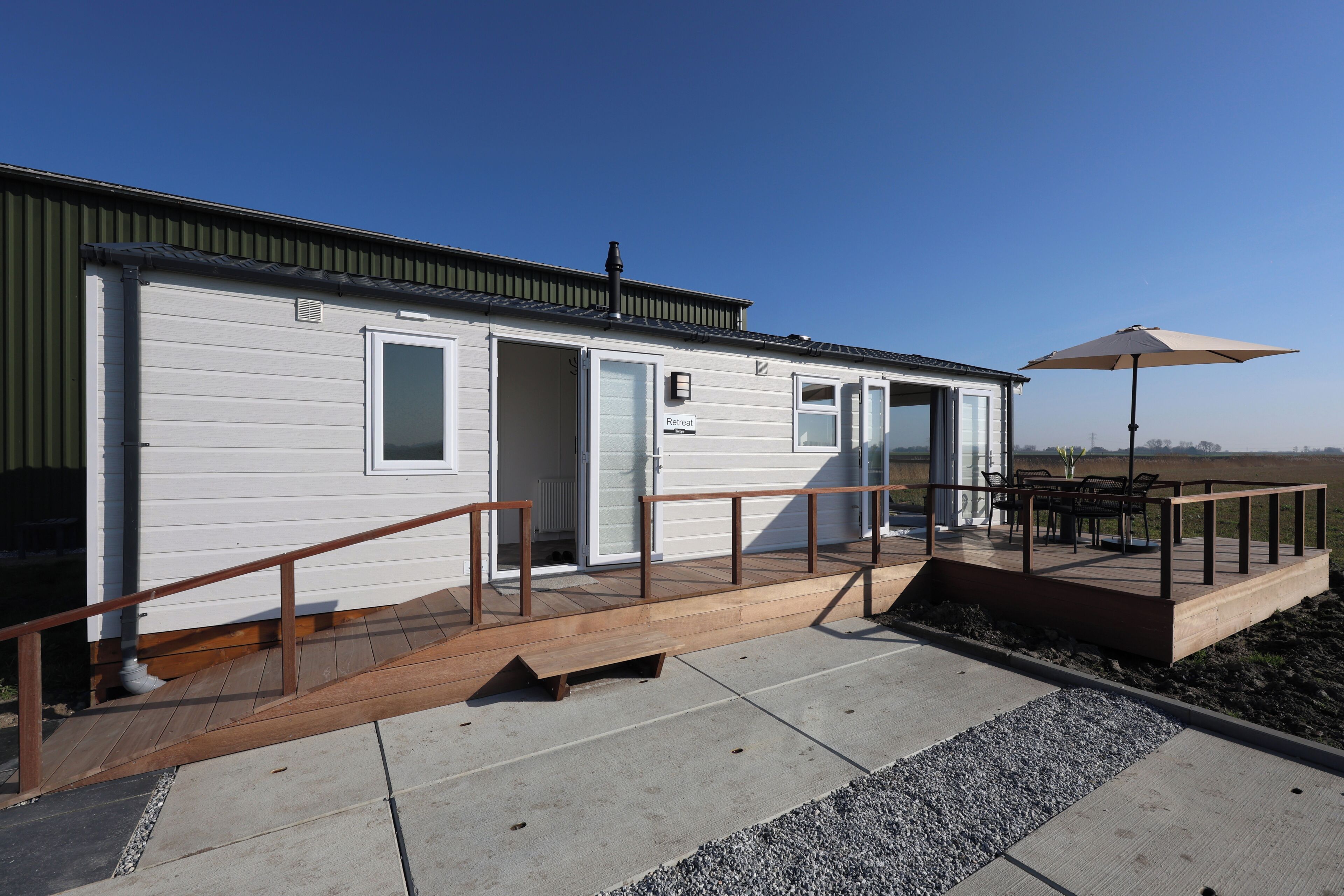 A single-story building with a covered outdoor seating area, a ramp leading to the entrance, and a clear sky.