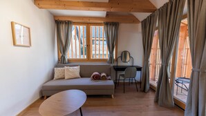 A room with a sofa, a round table, a desk, and large windows with curtains. - Hotel Old Coach House (Bled)