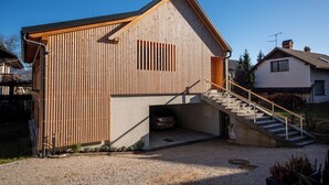 A wooden building with a garage, a staircase, and a clear sky. - Hotel Old Coach House (Bled)