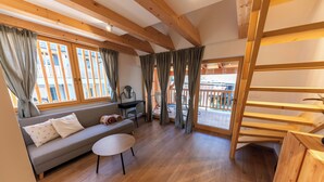 A cozy living room with a sofa, a small table, and a wooden staircase. - Hotel Old Coach House (Bled)