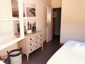 A bedroom with a bed, dresser, and artwork on the wall.