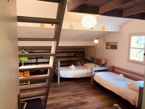 A compact room with bunk beds, a ladder, a desk, and a lamp.