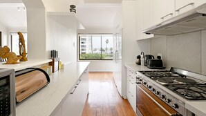 Een moderne keuken met een groot raam, roestvrijstalen apparatuur en een houten vloer.