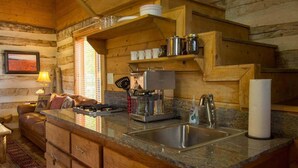 Une cuisine chaleureuse, aménagée dans le style d’un chalet, avec un intérieur en bois, une cuisinière intégrée, une machine à café et un évier.