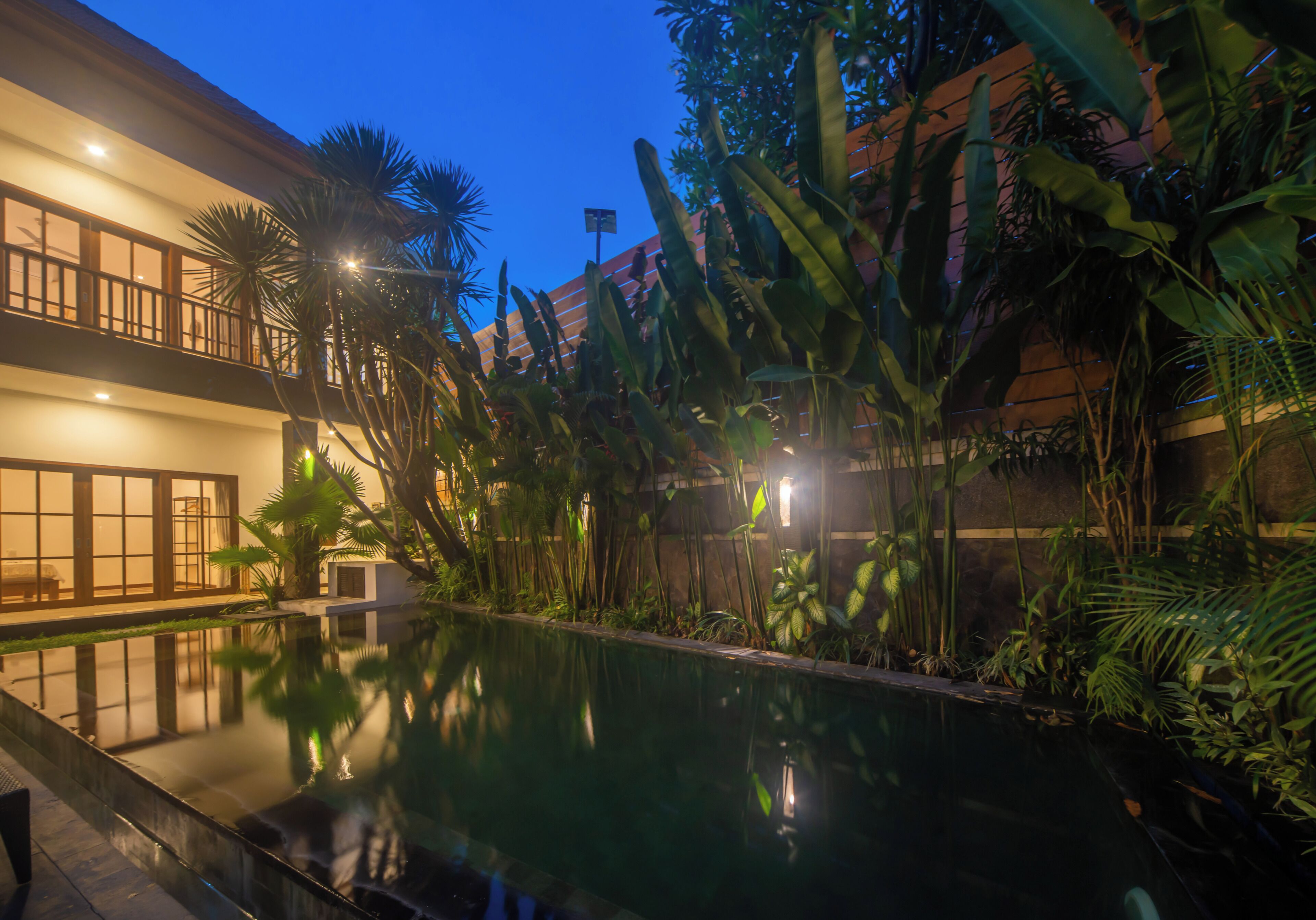 A pool surrounded by lush greenery and a building with large windows.