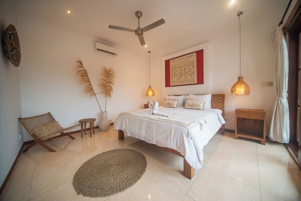 Une chambre à coucher comprenant un lit, un ventilateur de plafond, une table de chevet, une chaise et un élément décoratif mural.