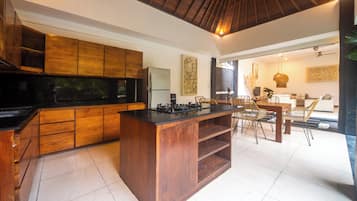 Una cocina moderna con armarios de madera, encimera negra y un comedor con sillas de mimbre.