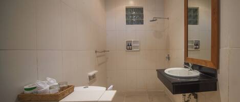 A bathroom with a white sink, a mirror, and a shower.