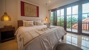 A bedroom with a large bed, a nightstand, a wall-mounted artwork, and a view through large windows. - 3BR Villa White Rose Central Canggu (Canggu)