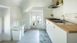 A narrow kitchen with white cabinets, a wooden countertop, and a view to the outside. - Elegant Lakefront Penthouse - Casa Barozzi (Luino)