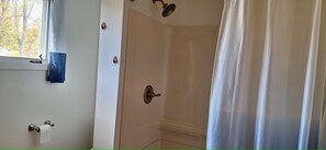 Ein Badezimmer mit Dusche, Handtuchhalter und Toilettenpapierhalter.