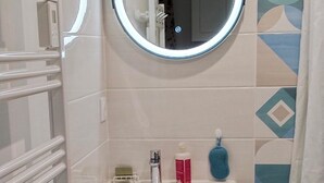 A bathroom with a white sink, a mirror, a towel rack, and a shower curtain. - Studio NATURE (Marboz)
