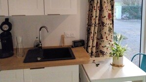 A kitchen with a sink, a clock, and a table with a potted plant. - Studio NATURE (Marboz)