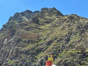 Un paysage montagneux caractérisé par un terrain rocheux et une structure qui ressemble à un bâtiment ou à une ruine, située sur le flanc de la montagne.
