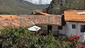 Ein Gebäude mit einem Ziegeldach, einem Balkon und einer Bergkulisse.