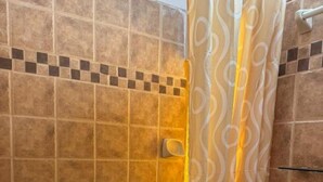 Ein Badezimmer mit Dusche, Toilette und Fliesenwänden.