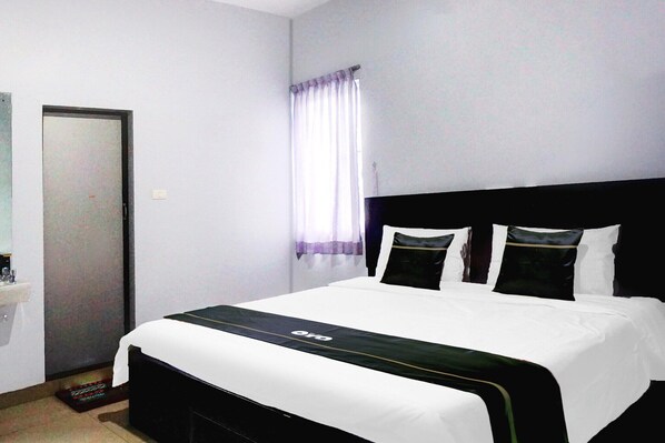 A hotel room with a bed, a door, a window with curtains, and a small sink.