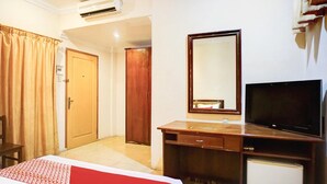 Une chambre d’hôtel comprenant un lit, un bureau, une télévision, un miroir et une armoire.