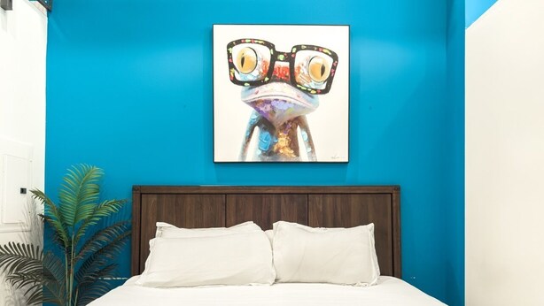 A bed with white bedding, a wooden headboard, and a blue wall.