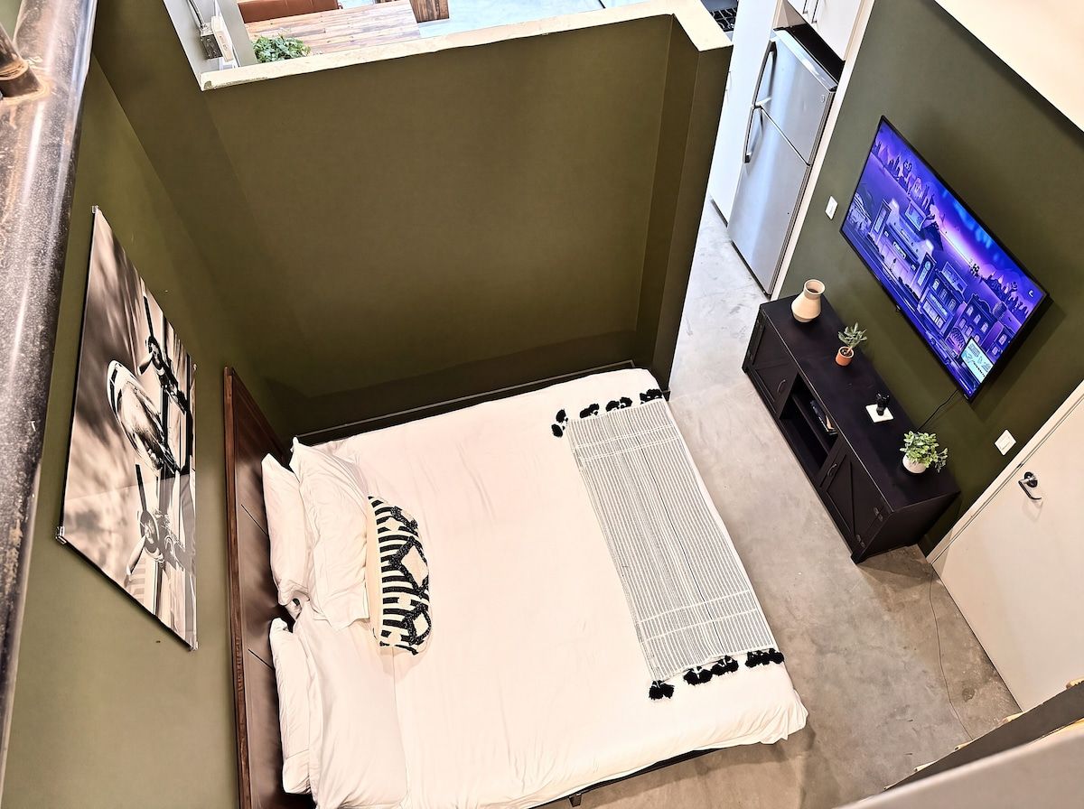 A bedroom with a bed, a television, and a small table with a plant.