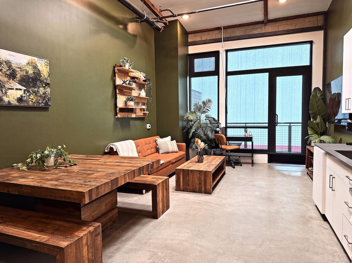 Un espace de vie moderne comprenant une grande table à manger en bois, un canapé et un coin cuisine.