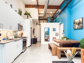 Une cuisine moderne avec des meubles blancs, des appareils en acier inoxydable et une table à manger en bois.