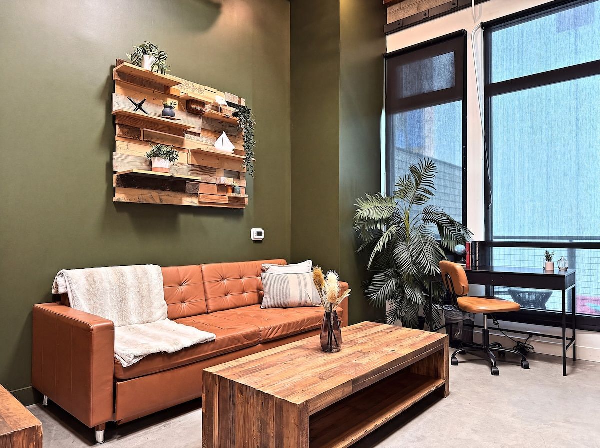 Stylish lounge with leather sofa, rustic décor, and bright work nook
