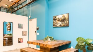 A room with a wooden table, benches, a white door, and a blue wall with a framed picture. - Stylish Downtown Loft Near Disney (Santa Ana)