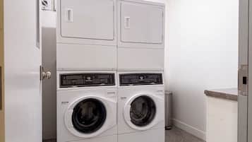 A laundry room with two stacked front-loading washing machines and a dryer.