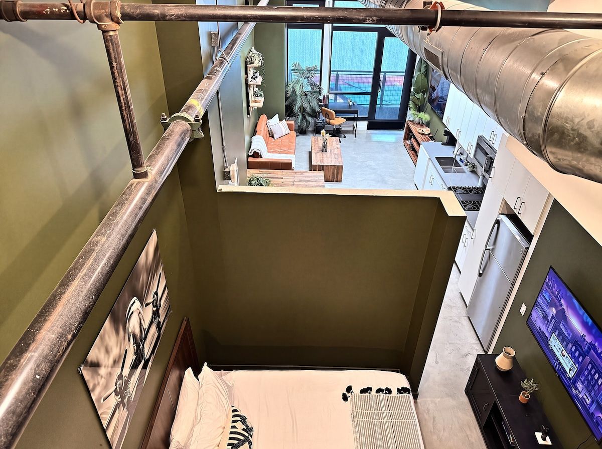 A room with a bed, a television, a window, and a view of the outside.