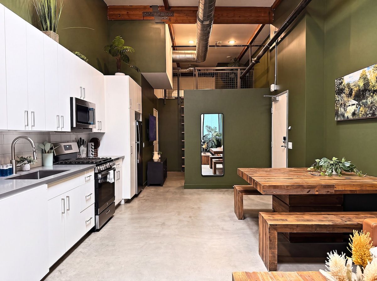 A modern kitchen with white cabinets, stainless steel appliances, and a wooden dining table.