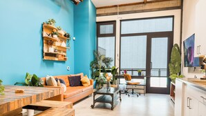 A modern office space with a wooden table, orange sofa, and a desk with a chair. - Stylish Downtown Loft Near Disney (Santa Ana)