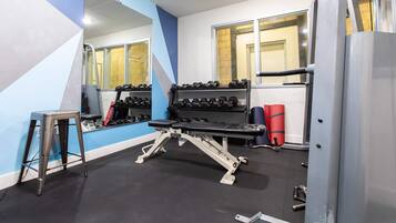 A gym with a bench press, dumbbells, and a squat rack.