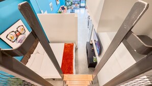 A modern interior with a staircase leading to a living area, a dining area, and a view through large windows. - Stylish Downtown Loft Near Disney (Santa Ana)