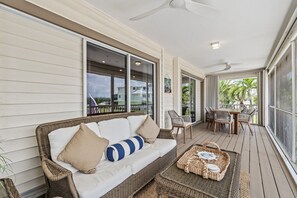Eine überdachte Veranda mit einem Korbsessel, Stühlen, einem Tisch und einem gewebten Korb.