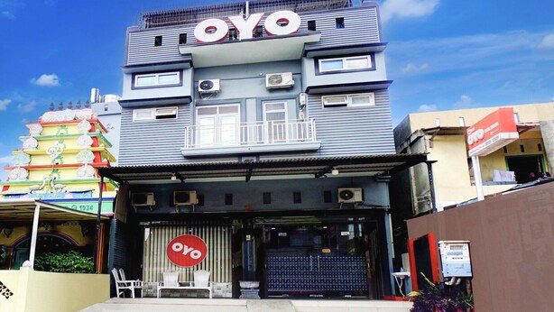 Un immeuble arborant une enseigne « OYO » bien visible, doté de climatiseurs et d’une entrée sécurisée par un portail.