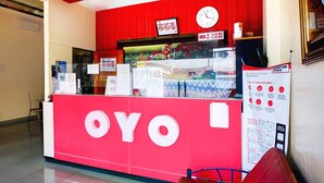 Un comptoir d’accueil aux couleurs rouge et blanc, une horloge et divers panneaux d’information.