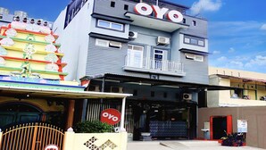 Un immeuble arborant une enseigne « OYO » bien visible, doté d’une entrée sécurisée et d’un balcon.