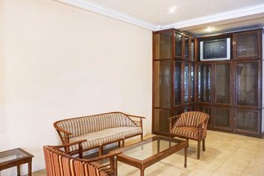 A living room with a sofa, armchairs, a glass coffee table, and a television on a cabinet.